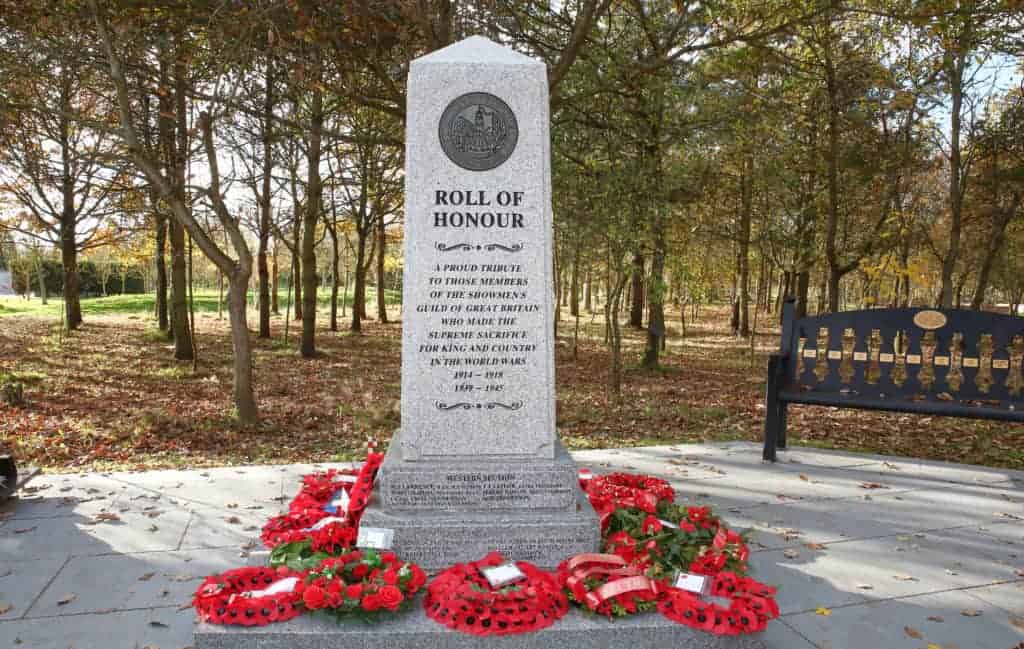 Photo - The Showmen’s Guild Memorial adorned with wreaths from Central Office, the Sections and individual showmen. Names of showmen from each Section who made the ultimate sacrifice are inscribed on all four sides of the base.
